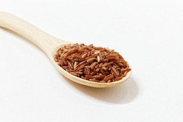 Thai Black or dark brown raw rice in a wooden spoon for a healthy diet. High fiber, vitamin, carbohydrate, minerals, and nutrition for healthy people. on the white background, isolate.
