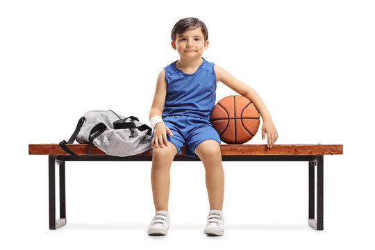 Little Basketball Player Sitting On A Wooden Bench Next To A Sports Bag