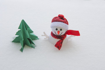 Winter background with snowman and toy christmas tree in snow