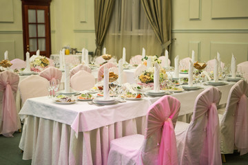 Elegantly decorated wedding table in restaurant. Served table with flowers and different dishes of European cuisine for celebration of wedding (birthday) in banquet house