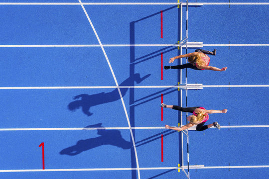 Runners crossing hurdles on tartan track