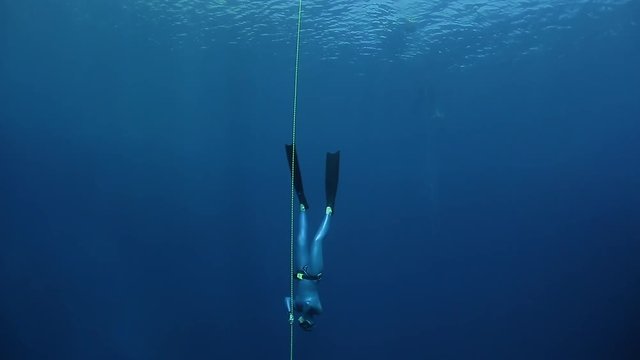 Woman freediver descends along the rope in a sea. Blue Hole, Dahab, Egypt.