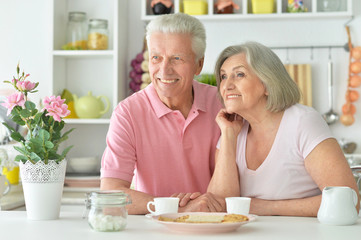 happy senior couple sitting at kitchen table 