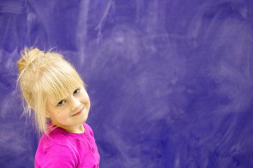 Obraz na płótnie Canvas Little girl smiling against chalkbaord.