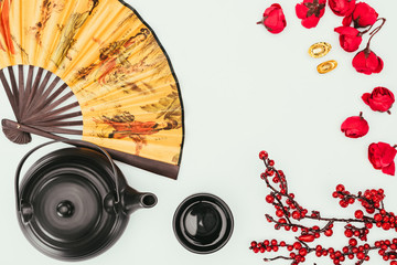 top view of chinese new year composition with tea and handheld fan isolated on white