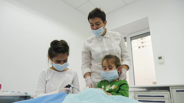 Children treat a toy with dentist using a diferent dental tools. Two little girl play the roles of dentist during a dental check-up