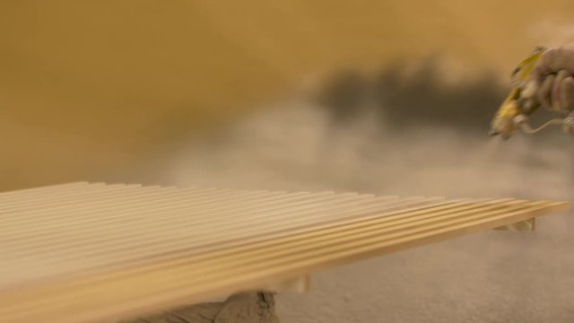 worker hand sprays polish to mdf planks