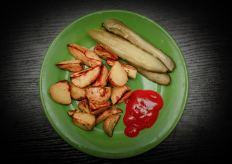 Baked potatoes on the with ketchup and pickled cucumbers on wooden background.
