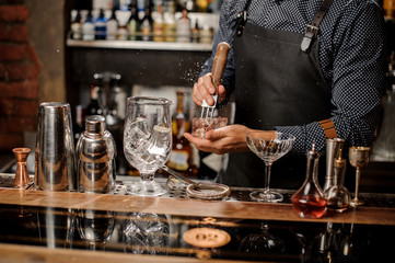 Barmans hands crushing a big ice cube