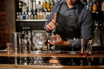 Bartenders hands crushing a big ice cube