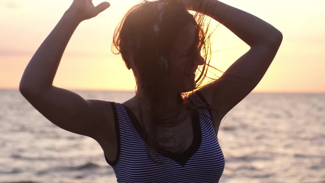 Young brunette happy woman have fun listening to music in headphones at beautiful sunset on the beach in slow motion 1920x1080