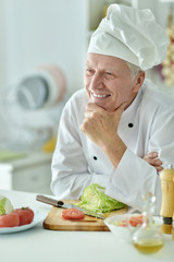 elderly male chef cooking salad