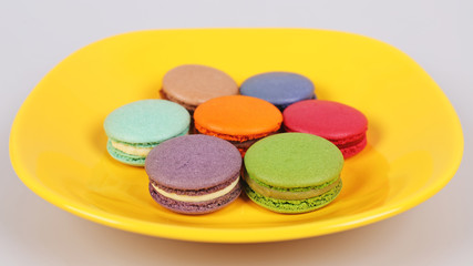Tasty delicious macaroons biscuits on yellow plate