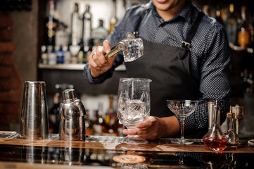 Bartender putting a big ice cube into the glass with help of special ice tongs