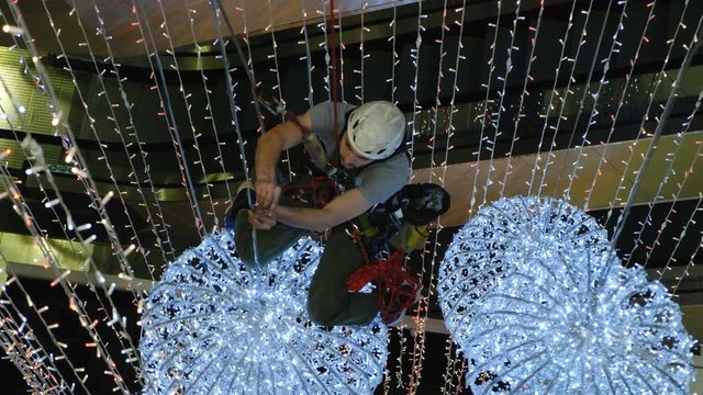 Industrial climber mounts Christmas decorations in the unsupported space in the shopping center