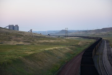 A long winding coal train passing through coal loading silos, open pit coal mining, Powder River Basin, Wyoming.