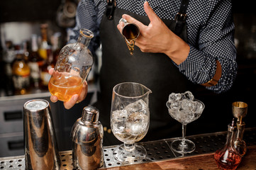 Barman adding a portion of syrup into the large cocktail glass