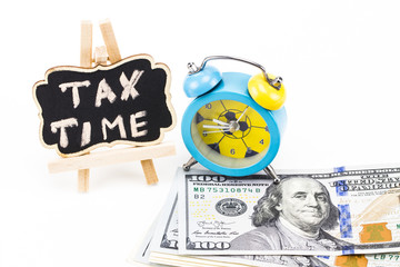 TAX TIME written on chalkboard with money and alarm clock on white background
