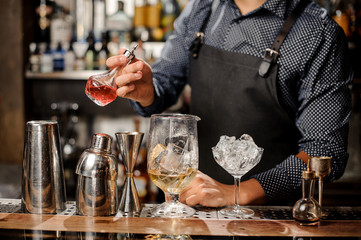 Barman pouring fruit syrup into the large cocktail glass