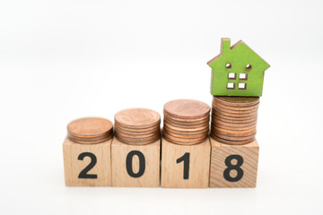 Miniature toy: wood block with 2018 and house and stack of coins on its , business ,financial, Success, Business Growth concept.