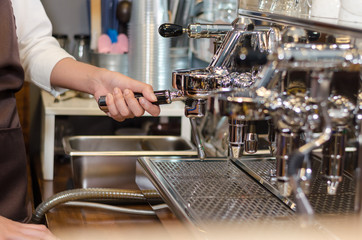 Girl barista bartender waiter in uniform making coffee at the bar
