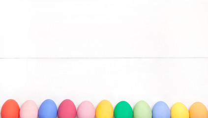 Easter composition with colored eggs on wooden white background with copy space.