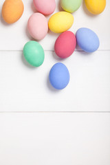 Easter composition with colored eggs on wooden white background with copy space.