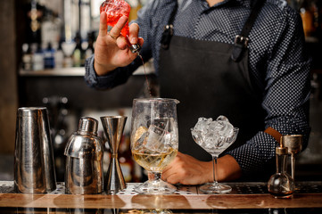 Bartender pouring fruit syrup into the large cocktail glass