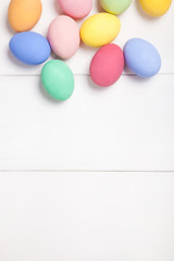 Easter composition with colored eggs on wooden white background with copy space.