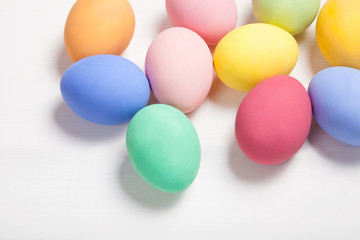 Easter composition with colored eggs on wooden white background with copy space.