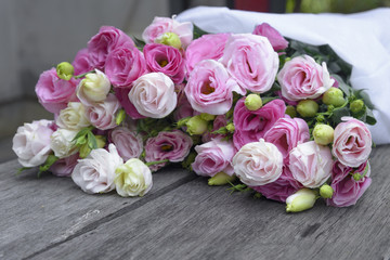 Beautiful bouquet of pink roses wrap with white paper on wooden table
