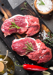 Fototapeta na wymiar Raw beef steak with herbs and ingredients on cutting board. Top view.