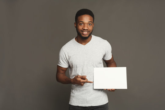 Picture of young african-american man holding white blank board