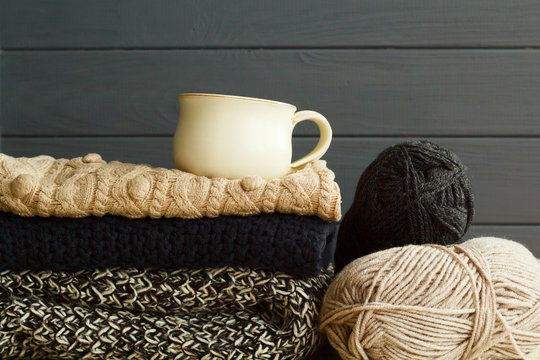 Picture of cozy sweaters and cup of coffee or tea over grey background