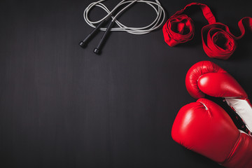 Professional red boxing gloves, wraps, and skipping rope on black background with copy space. - Powered by Adobe