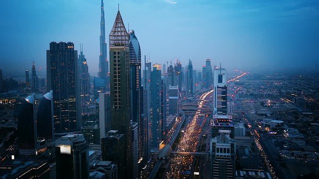 Downtown Dubai skyscrapers at sunset. Scenic aerial view of famous highway with fast moving traffic. 