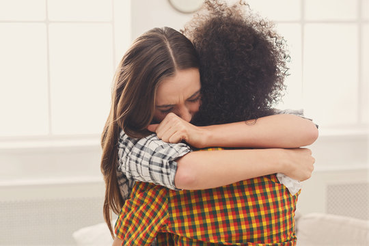 Woman hugging her depressed friend at home
