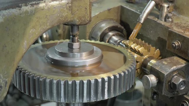 The machine on the plant, which is trenching the alluminium circle. The detail is turning anti clockwise and the cutting machine is twisting from up to down. The oil is being poured to the workpiece