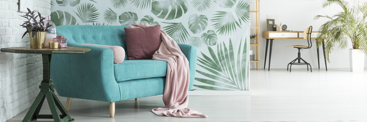 Turquoise sofa against floral wallpaper