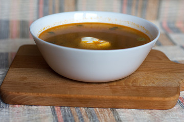 Vegetable soup with sour cream in a white bowl on a wooden stand and a towel