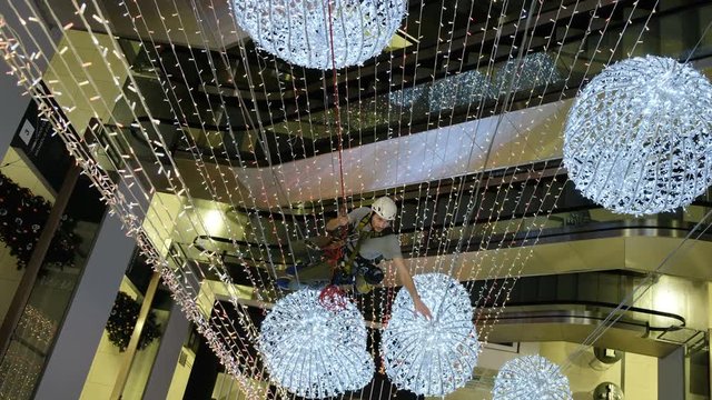 Industrial climber mounts Christmas decorations in the unsupported space in the shopping center