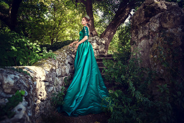 Young woman wearing a green dress explores a magical forest