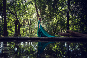 Young woman wearing a green dress explores a magical forest