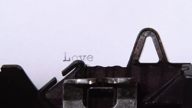 Writer types a love on a typewriter. Close up