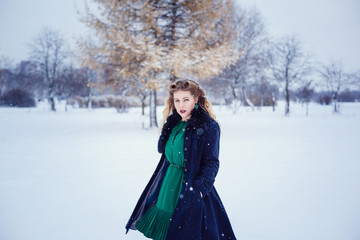 Fototapeta na wymiar Young beautiful woman walking in a park and breathing fresh winter air and feeling wonderful