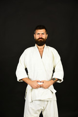 Man with beard in white kimono on black background