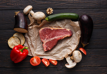 Raw t-bone steak on craft papper on dark background