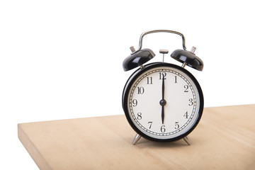 Naklejka premium black alarm clock on wood table at morning isolated on white background.