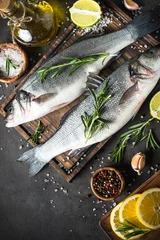 Wall murals Fish Fresh fish seabass on black stone table/ Top view.