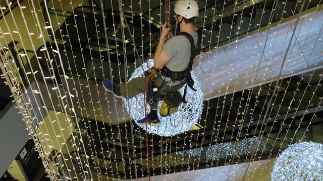 Industrial climber mounts Christmas decorations in the unsupported space in the shopping center